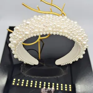 Detailed view of wide baroque sponge headband with creamy white pearls on golden stand