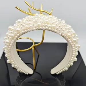 Close-up of luxury padded headband with white faux pearls on a gold display stand