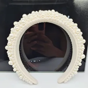 Detailed view of Baroque padded headband with multi-sized white pearls on cream fabric