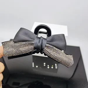 Detail of elegant black hair claw clip featuring sparkling silver rhinestones and ribbon