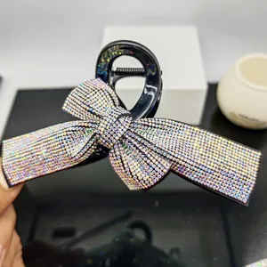Detail shot of a large black hair claw clip with colorful AB rhinestones on a bow