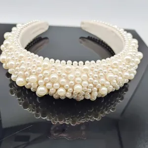 Baroque style cream headband with sponge padding and pearls on a black surface