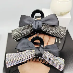 Detailed view of large black satin bow hair claws with sparkling rhinestone accents
