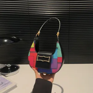 Minimalist colorful patchwork crescent hobo bag with gold buckle on a stylish desk setting