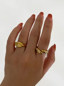 Detail of gold-plated evil eye ring and twisted band with cubic zirconia on hand