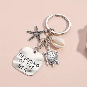 Detail of silver starfish and turtle charms with Dreaming of the Sea engraved plate