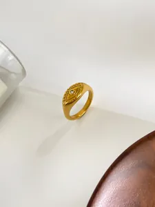 Macro detail of gold plated evil eye signet ring featuring a centered zircon stone