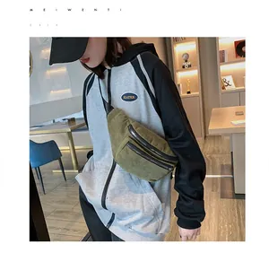 Olive green corduroy crossbody chest bag featuring dual metal zipper pockets worn by a model