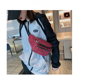 Detail of red corduroy waist bag showing double zipper structure and soft ribbed texture