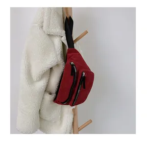 Close-up of wine red corduroy chest bag featuring a textured finish and dual silver zippers