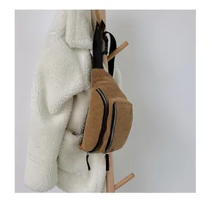 Detail view of brown corduroy waist bag with dual black zippers and adjustable strap