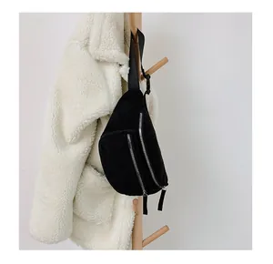 Detail of black corduroy chest bag with silver zippers hanging on a wooden rack