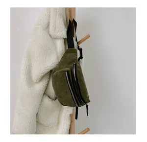 Close-up of olive green corduroy fanny pack showing metallic zippers and strap texture