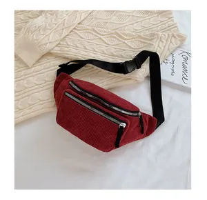 Detail of burgundy corduroy waist bag with dual silver zippers and adjustable strap