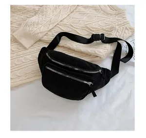 Close-up of black corduroy chest bag with silver zippers and plastic buckle strap