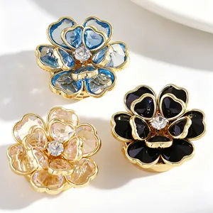 Primer plano de tres elegantes gemelos florales en azul, negro y champán con cristales.