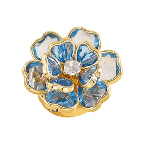 Primer plano de gemelos con forma de flor de cristal azul y blanco y pétalos dorados