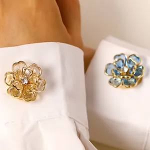 Detalle de elegantes gemelos en forma de flor con pétalos de cristal en puño blanco.