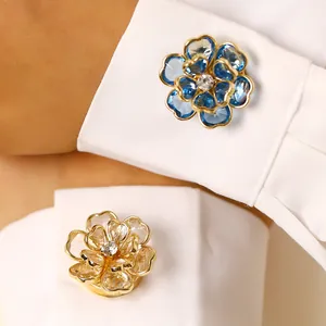 Detalle de gemelos de flor de cristal azul y champán en puños de camisa blanca