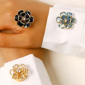 Detalle de elegantes gemelos de flores en negro, azul y transparente en puño de camisa