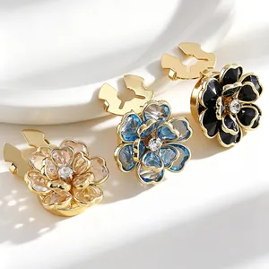 Primer plano de elegantes gemelos de flores en dorado, azul y negro con detalle de cristal.