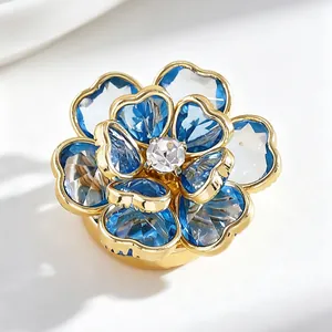 Vista detallada de un gemelo de lujo en forma de flor de cristal azul con borde dorado