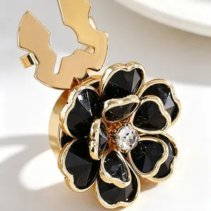 Detalle macro de un lujoso gemelo floral con pétalos de esmalte negro y acabado dorado