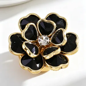 Primer plano detallado de un gemelo con forma de flor negra, borde dorado y cristal