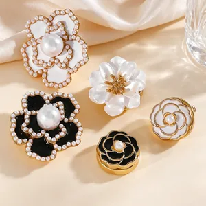 Primer plano detallado de elegantes broches de flores de esmalte con perlas blancas