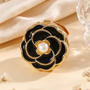 Detalle macro del gemelo de camelia en esmalte negro con una perla blanca central