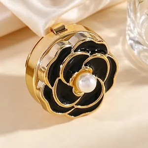 Primer plano de un gemelo de flor en esmalte negro con una perla central y acabado dorado