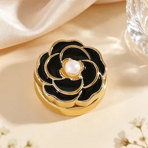 Detalle de gemelo de camelia negra elegante con bordes dorados y perla central