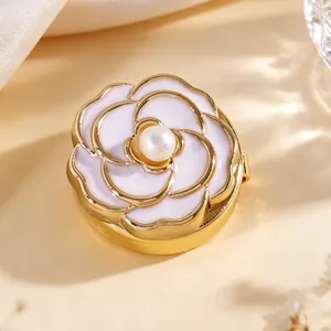 Detalle de primer plano de gemelo camelia esmaltada rosa con perla y base dorata