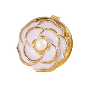 Detalle de gemelo de flor de esmalte rosa con perla y acabado dorado.