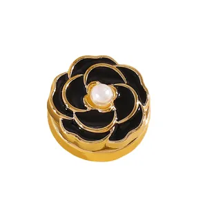 Detalle macro de un gemelo de flor de camelia en esmalte negro con borde dorado y perla