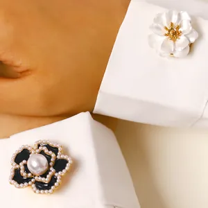 Primer plano de gemelos elegantes con forma de flor y perlas en los puños de camisa.