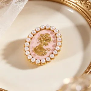 Vista detallada de un broche camafeo vintage de lujo con silueta dorada y borde de perlas