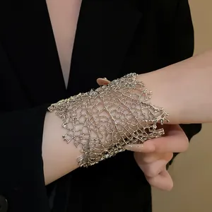 Primo piano di un bracciale rigido traforato a foglia color argento sul polso di donna.