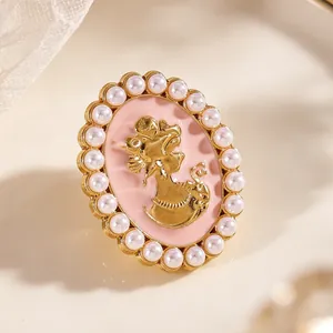 Detalle macro del gemelo de esmalte rosa con retrato dorado y borde de perlas.