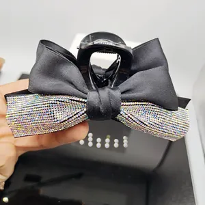 Detail of elegant black ribbon bow hair claw clip with sparkling colorful rhinestones