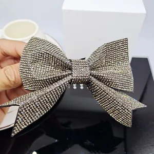 Detailed view of a large bow hair clip featuring dark grey rhinestones on a metal base