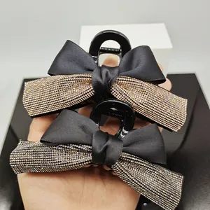 Close-up of elegant black ribbon bow hair claws with sparkling rhinestones in gold and silver