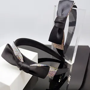 Dettaglio del cerchietto in raso nero con strass sfumati scintillanti sul fiocco