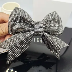 Detail of a large bow hair clip featuring dense sparkling rhinestones in a hand view