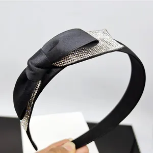 Dettaglio di una fascia per capelli in raso nero con un grande fiocco decorato con cristalli