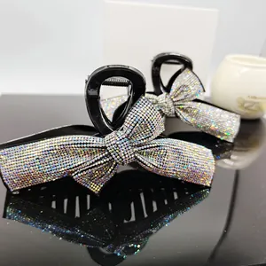 Detailed view of two elegant bow hair claws with sparkling AB rhinestones on black acrylic