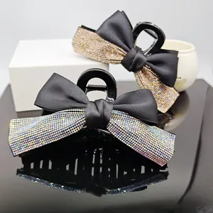 Detail of two black satin bow hair claws with colorful sparkling rhinestones