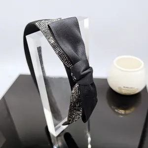 Dettaglio del cerchietto in raso nero con maxi fiocco e strass luminosi applicati