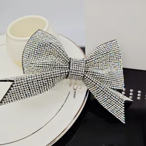 Close-up of a sparkling bow hair clip with full silver rhinestones on a white plate