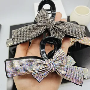 Close-up of bow-shaped hair claws featuring silver-gray and AB colorful rhinestones